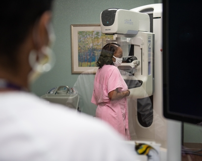 A Black woman in a pink robe gets a mammogram at Novant Health, a key breast cancer screening.
