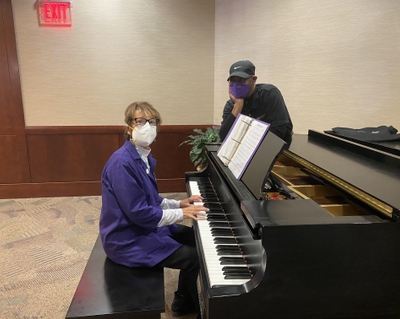 Claudia sits by a piano with her hands poised to play