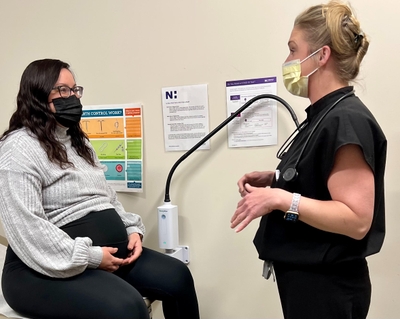 Jennifer Keiger talking with a patient. The patient is sitting on an exam chair.