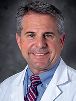 Dr. Joseph Pino is smiling and wearing a white lab coat.