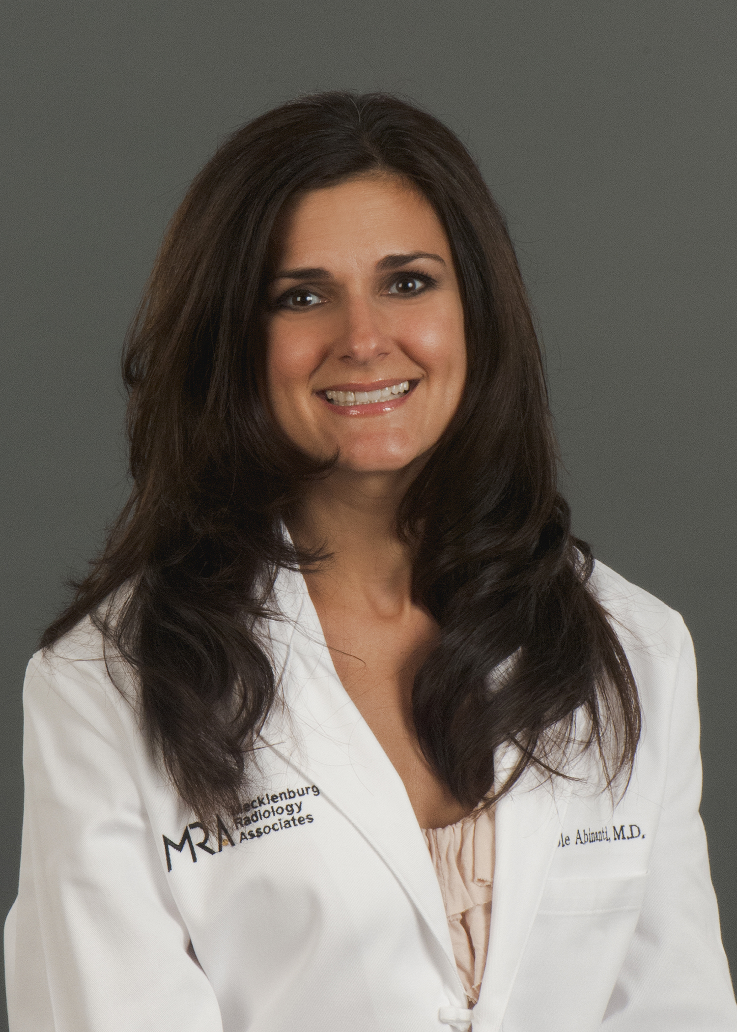 Dr. Nicole Abinati is wearing a white lab coat and smiles into the camera.
