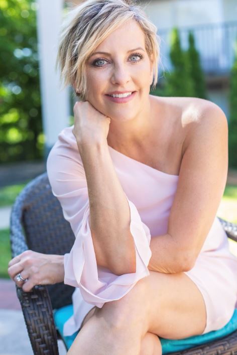 Ashlee Jenkins, a breast cancer survivor, smiles for a photo in a beautiful peach dress. 