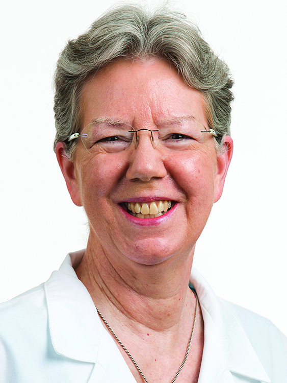 Dr. Judith Hopkins, a female oncologist, smiles for a photo in a white lab coat.