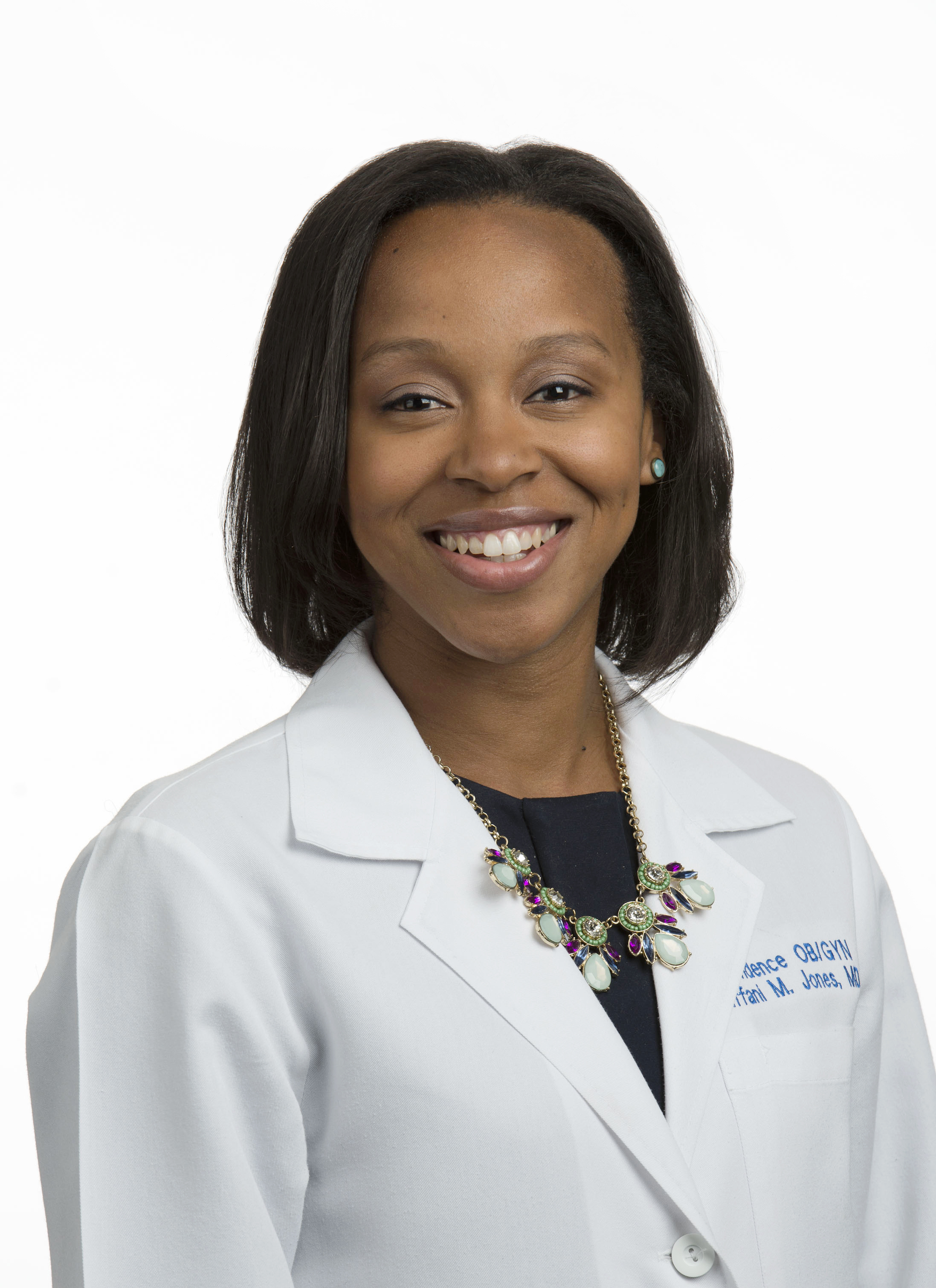Dr. Tiffani Jones is wearing a white lab coat and is smiling into the camera.