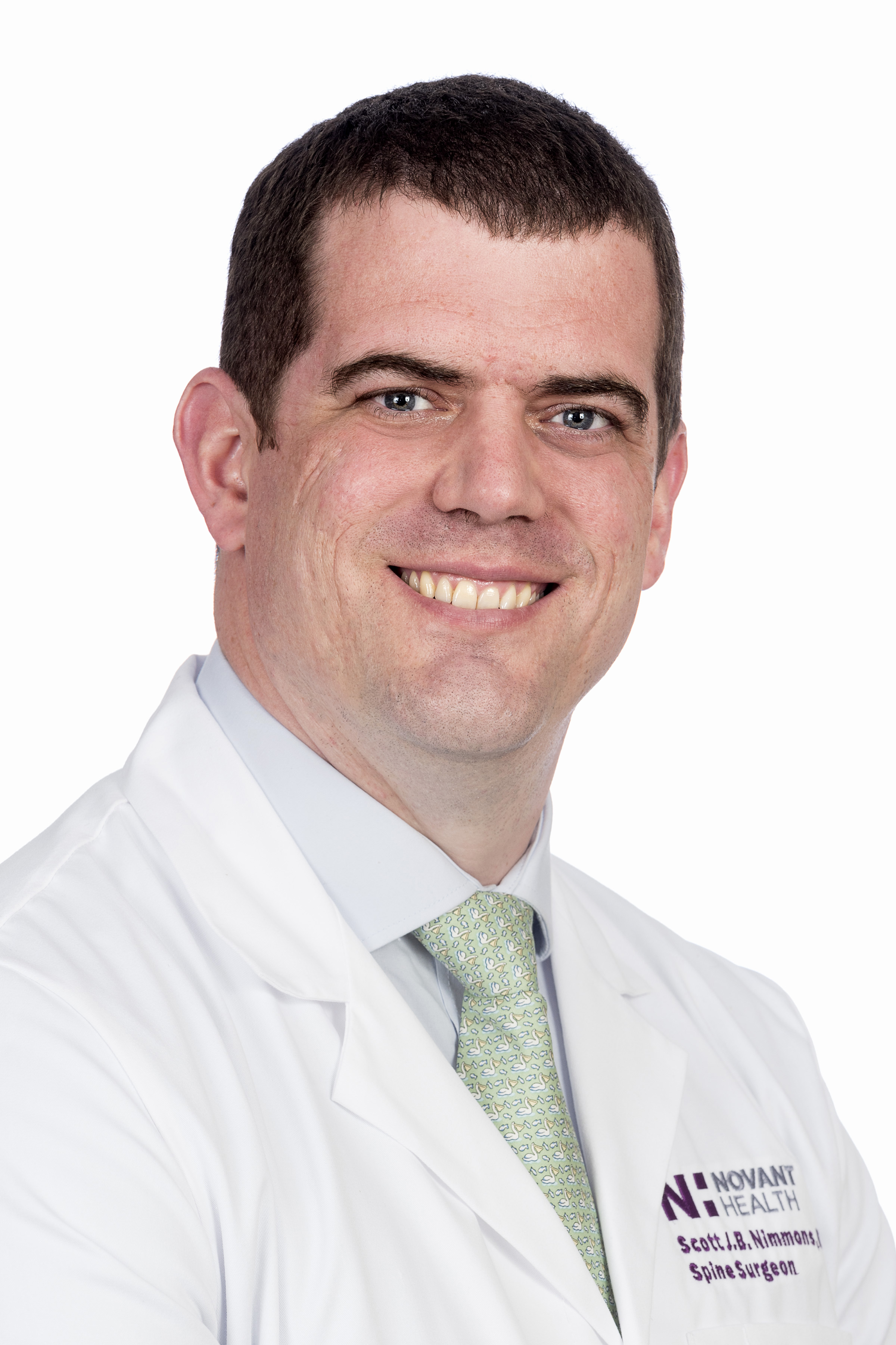 Dr. Scott Nimmons is wearing a white lab coat and smiles into the camera.