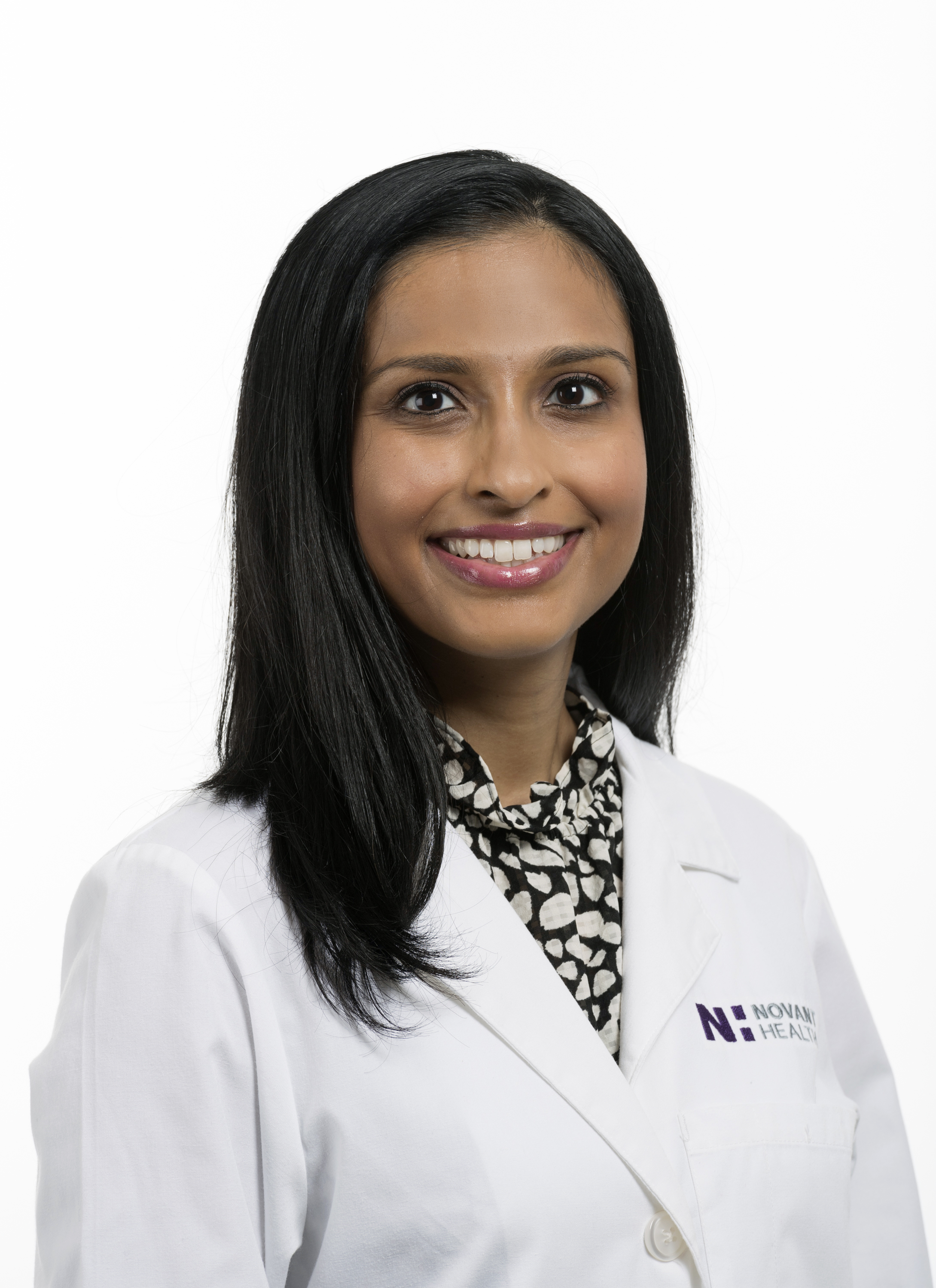 Dr. Ankita Langan is wearing a white lab coat and is smiling into the camera