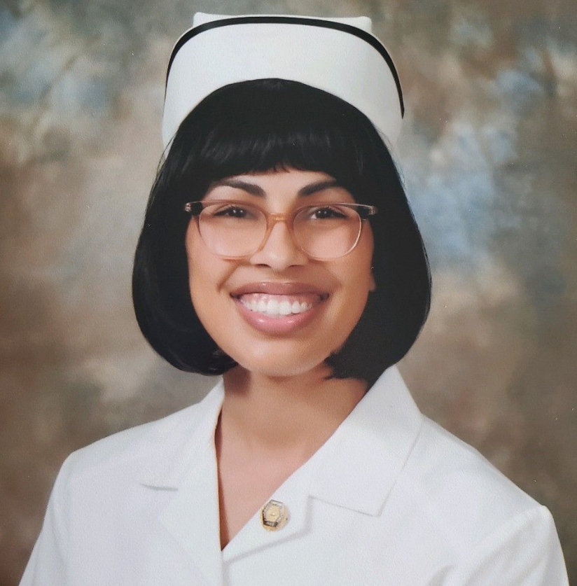 Tanya Harless wears a white nurse's cap and uniform while smiling at the camera