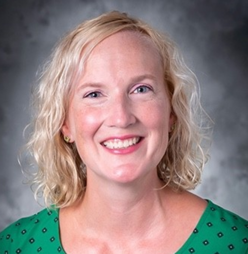 Ruth wears a green blouse and smiles at the camera