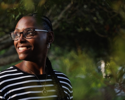 Kashinda Carter smiles while standing outside with trees behind her.
