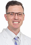 Dr. Devin Simon wears a white coat and smiles.