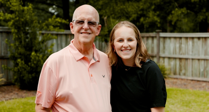 Robert Hines, left, and Abby Hines, right, stand side-by-side and smile at the camera in a grassy yard.