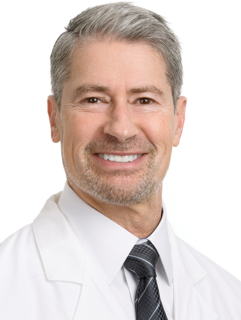 Dr. Jeffrey Everett wears a white coat and smiles.