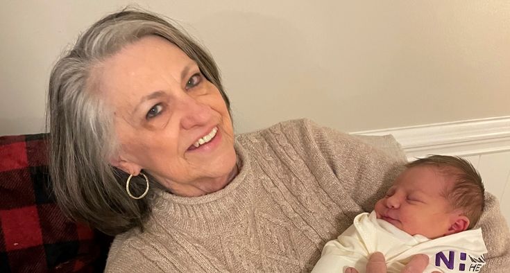 Linda Hackler holds a newborn baby and smiles at the camera.