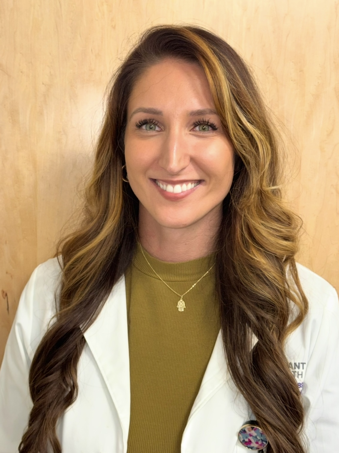 Belma Ceric wears a white coat and smles.