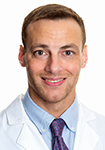 Dr. Brian Kelley wears a white coat and smiles.