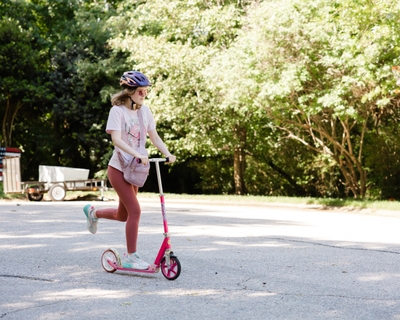 Ellie Strickland wears a helmet and rides a scooter.