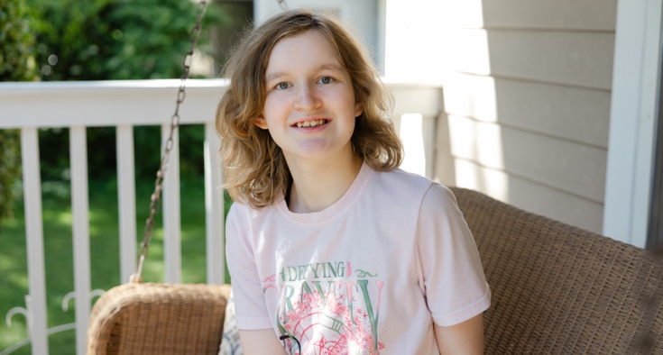 Ellie Strickland sits on a wicker porch swing and smiles at the camera.