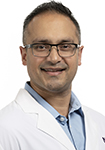 Dr. Ashish Jain wears a white coat and smiles at the camera. 