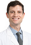 Dr. Logan Rhea wears a white coat and smiles.