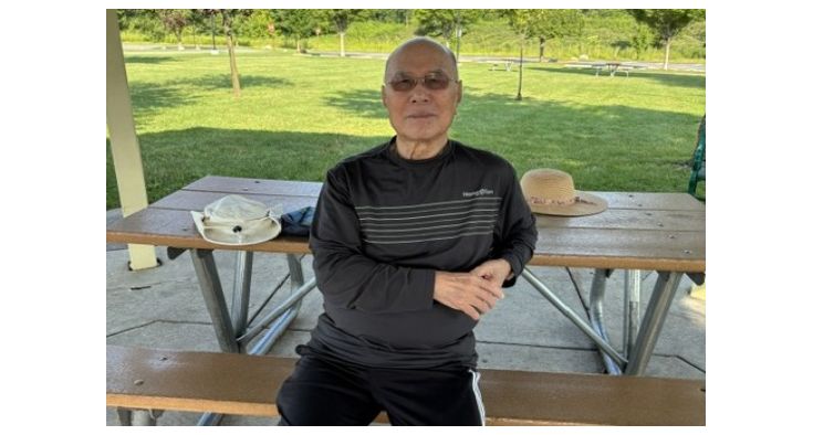 Richard Chang sits on a picnic table at a park.