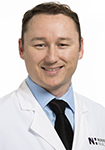 Dr. Timothy Ewald wears a white coat and smiles.