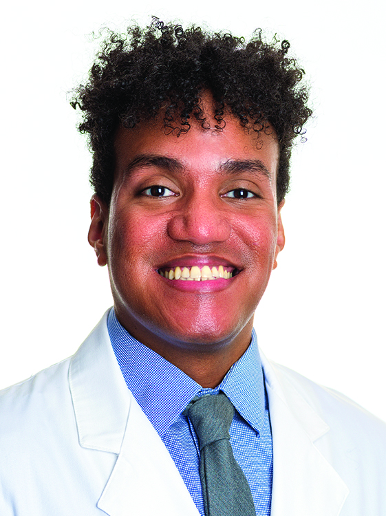 Nurse practitioner Anthony Horn wears a white coat and smiles.