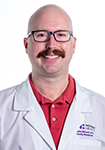 Dr. John Bissett wears a white coat and smiles.