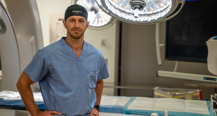 Dr. Dale Coffey wears scrubs and stands in an operating room.
