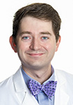 Dr. James Coley wears a white coat and smiles.
