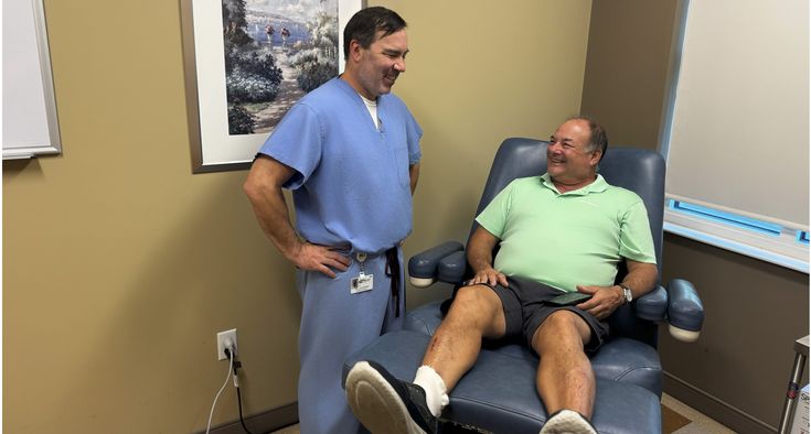 Novant Health patient Michael Casavant sits in a chair and talks with Dr. Chris Culpepper who is standing next to him.