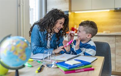 Young woman playing with a little boy at a desk.