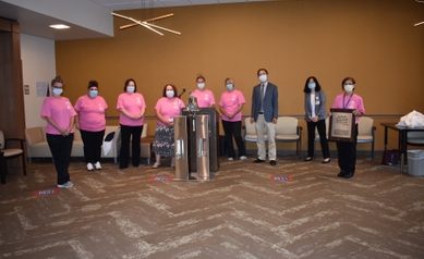 Doctors and nurses encircle a silver bell. 