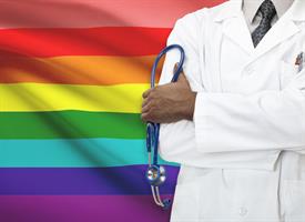 Physician standing in front of a pride flag