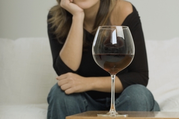 Woman sitting with glass of wine on a table in front of her