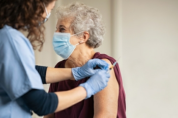 Doctor giving Johnson and Johnson vaccine to senior woman at a rural clinic.