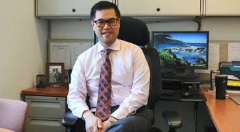 Dr. Chunkit Fung sits at his desk in his office at the Wilmot Cancer Institute