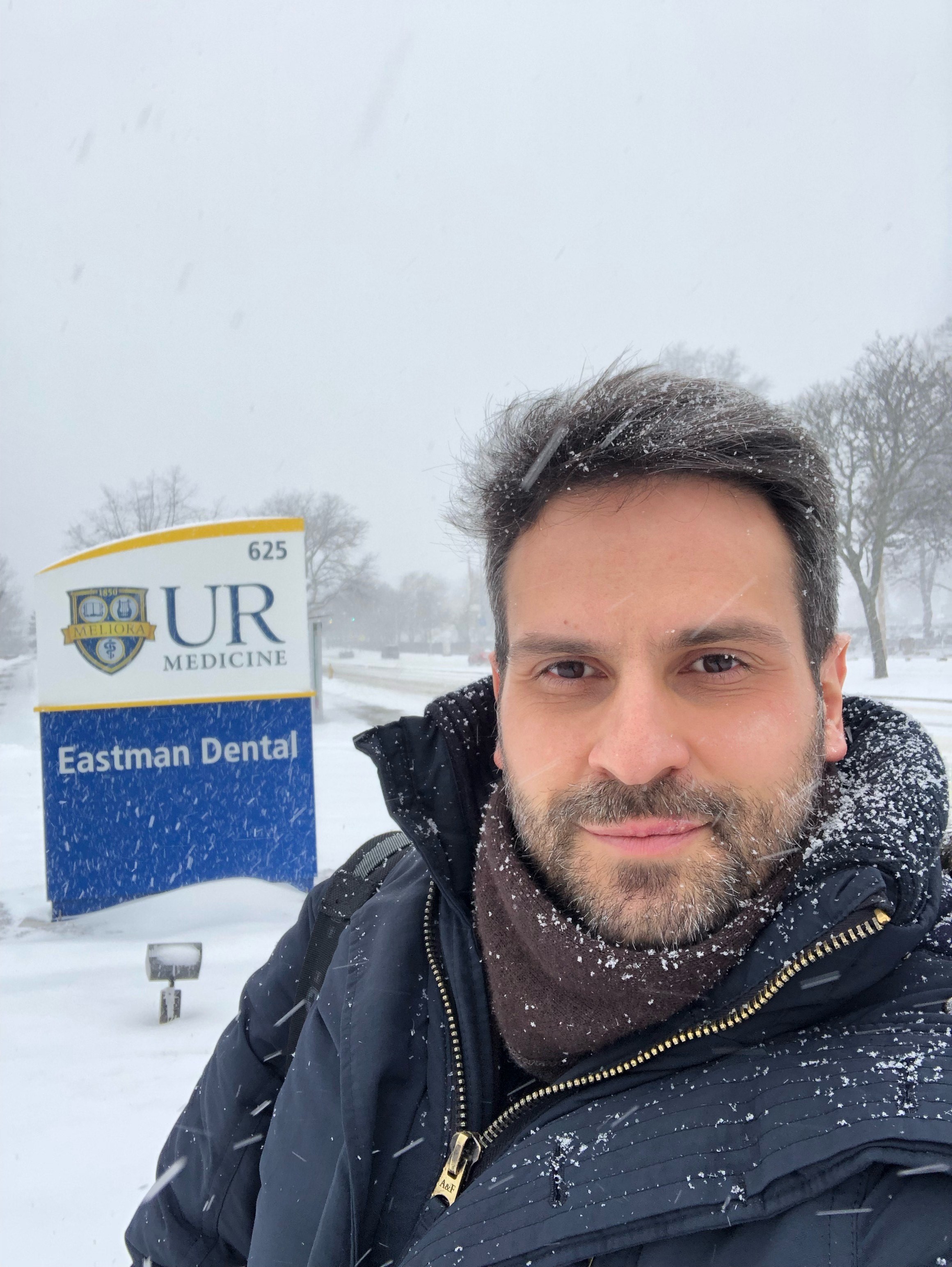 Dr. P in front of the Eastman Dental sign outside in the snow