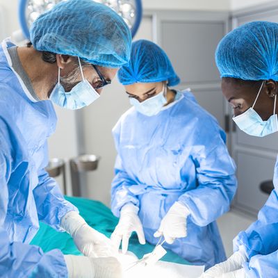 Group of surgeons doing surgery in hospital operating theater. Medical team doing critical operation. Group of surgeons in operating room with surgery equipment. Modern medical background