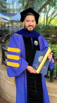 Photo of Carlos Ortiz-Bonilla, Ph.D., wearing University of Rochester graduation robe.