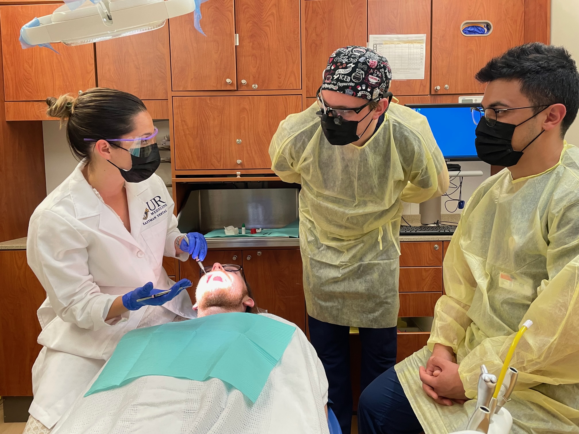 Dr. Tsigarida seated near the patient and speaking with two residents standing nearby.