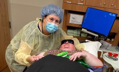 Dr. Stephens standing next to Brenda, who is lying on a stretcher in a dental treatment room.