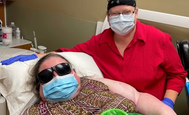 The patient Brenda is on the stretcher and sister Bonnie is seated nearby posing for the camera.