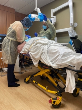 Doctor and dental assistant treat the patient who stays on the stretcher. 