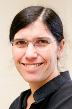 Patricia White headshot, she is smiling wearing a dark collared shirt, her dark hair is pulled neatly back, and is wearing glasses.