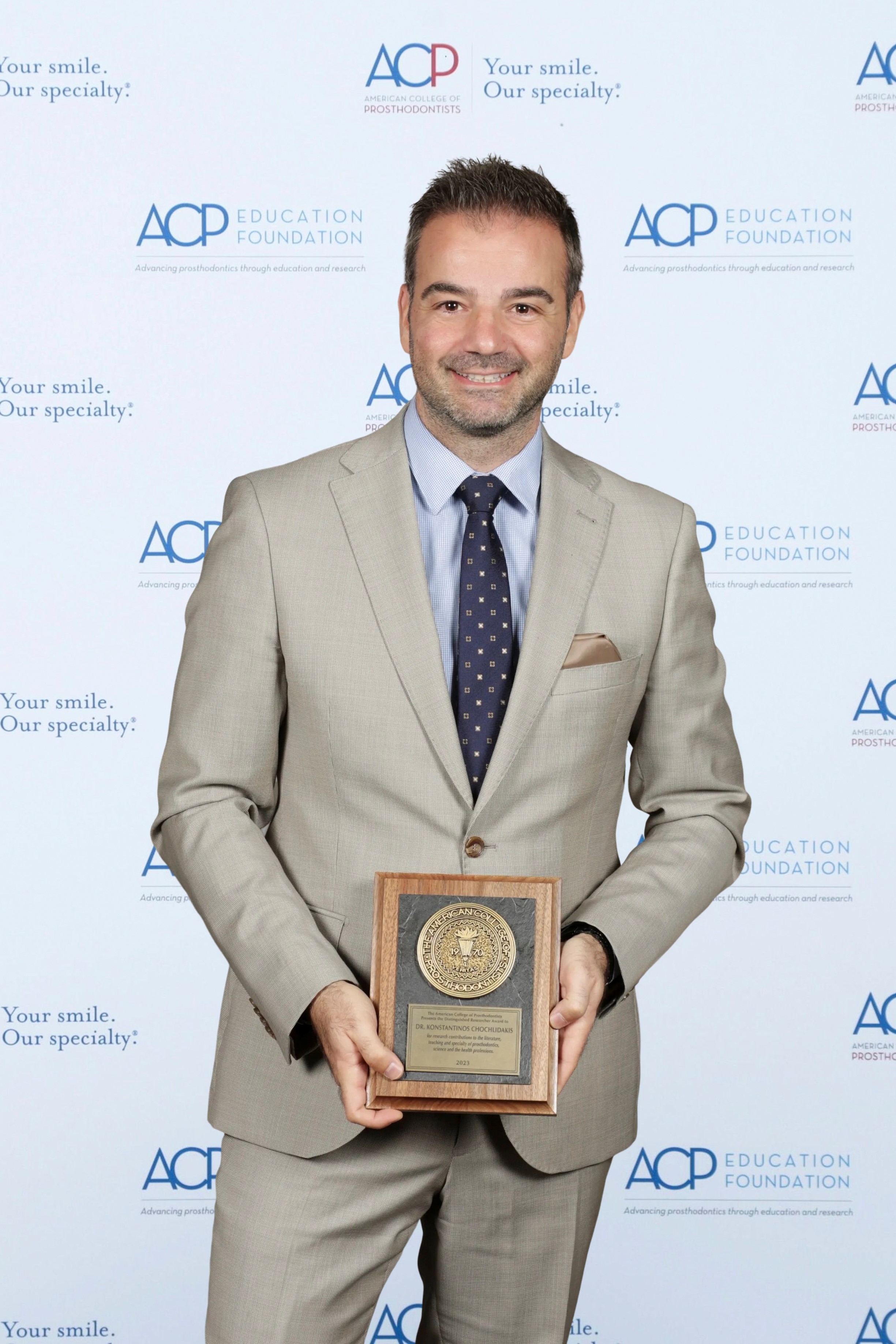 Dr. Chochlidakis holding the award, looking at camera