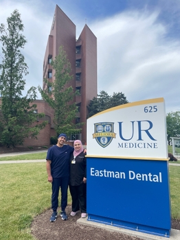 The couple standing outside by the Eastman Dental sign