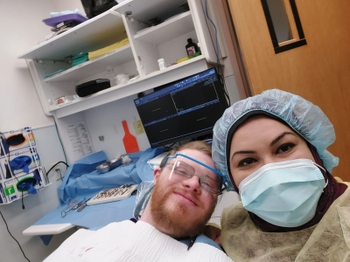 Furqan sitting next to a patient in a dental chair.