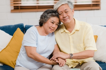 An aging couple embraces in a side hug.
