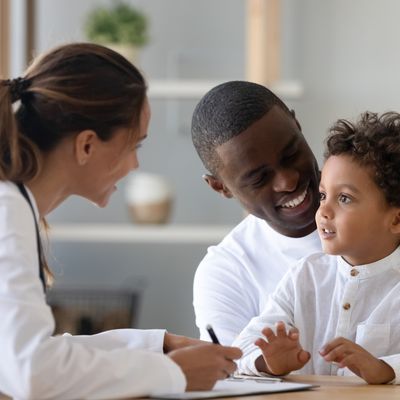 Cheerful young female pediatrician and black father listening to patient.