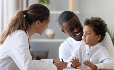 Cheerful young female pediatrician and black father listening to patient.